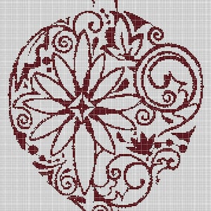 Puede incluir: Un adorno navideño de corazón de color marrón con un diseño floral y un lazo en la parte superior.