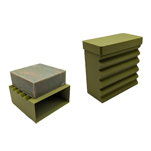 May include: Two green soap dishes with a ribbed design. One dish has a bar of soap on top.