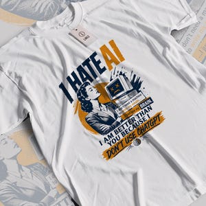 Może przedstawiać: Biały t-shirt z krótkim rękawem z grafiką przedstawiającą osobę patrzącą na monitor komputera. Tekst brzmi: I HATE AI, I don't need a machine to write my emails, I just use my BRAIN, I AM BETTER THAN YOU BECAUSE I DON'T USE CHATGPT.