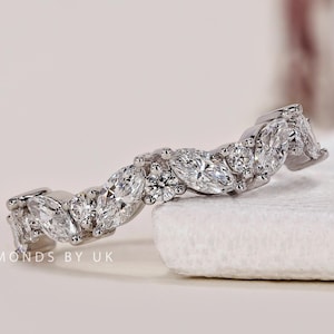 May include: A delicate, silver band with a wave-like design featuring a row of marquise and round diamonds.
