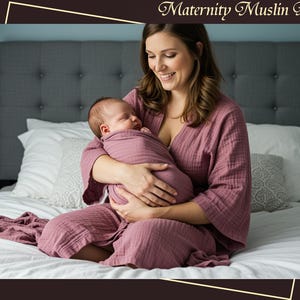 Puede incluir: Una mujer con una bata de muselina de maternidad malva, sosteniendo a un bebé recién nacido envuelto en una manta a juego. El texto "Maternity Muslin Robes" está en la parte superior de la imagen.