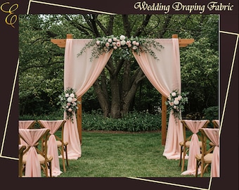 May include: A wooden wedding arch draped with flowing blush fabric and adorned with floral arrangements. The scene includes chairs with matching fabric accents, set on a green lawn, creating an elegant outdoor ceremony setting. The text "Wedding Draping Fabric" is at the top.