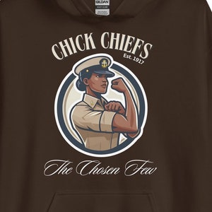 Puede incluir: Sudadera con capucha marrón con un gráfico blanco de una mujer con un sombrero de marinero azul marino y uniforme con el texto "Chick Chiefs Est. 1917" y "The Chosen Few" impreso debajo del gráfico.