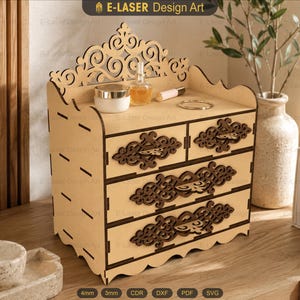 May include: A light-coloured wooden desktop organiser featuring three drawers with dark brown laser-cut decorative filigree handles. The top surface includes a scalloped back panel with intricate scrollwork and cutouts for storage.
