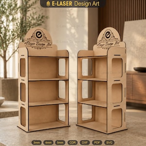 Puede incluir: Dos expositores de madera de color claro con tres estantes cada uno. La parte superior de cada expositor presenta un encabezado redondeado con el texto E-LASER Design Art y un logotipo circular. Los paneles laterales tienen recortes rectangulares y bordes oscuros.