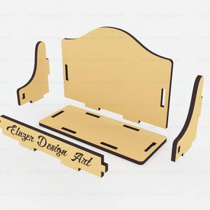 Peut inclure: Un kit de bricolage en bois clair compos&eacute; de cinq pi&egrave;ces plates d&eacute;coup&eacute;es au laser, pr&ecirc;tes &agrave; &ecirc;tre assembl&eacute;es. Le panneau avant porte l'inscription Elazer Design Art dans une police cursive sombre. Le kit comprend un panneau arri&egrave;re, une base, deux supports lat&eacute;raux et une pi&egrave;ce avant.
