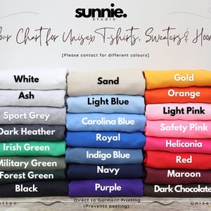 May include: A color chart for unisex t-shirts, sweaters, and hoodies from Sunnie Studio. The image displays three vertical stacks of folded fabric in various colors, each labeled with its name, including white, sand, gold, ash, light blue, orange, sport grey, Carolina blue, light pink, dark heather, royal, safety pink, Irish green, indigo blue, heliconia, military green, navy, red, forest green, purple, black, and dark chocolate.