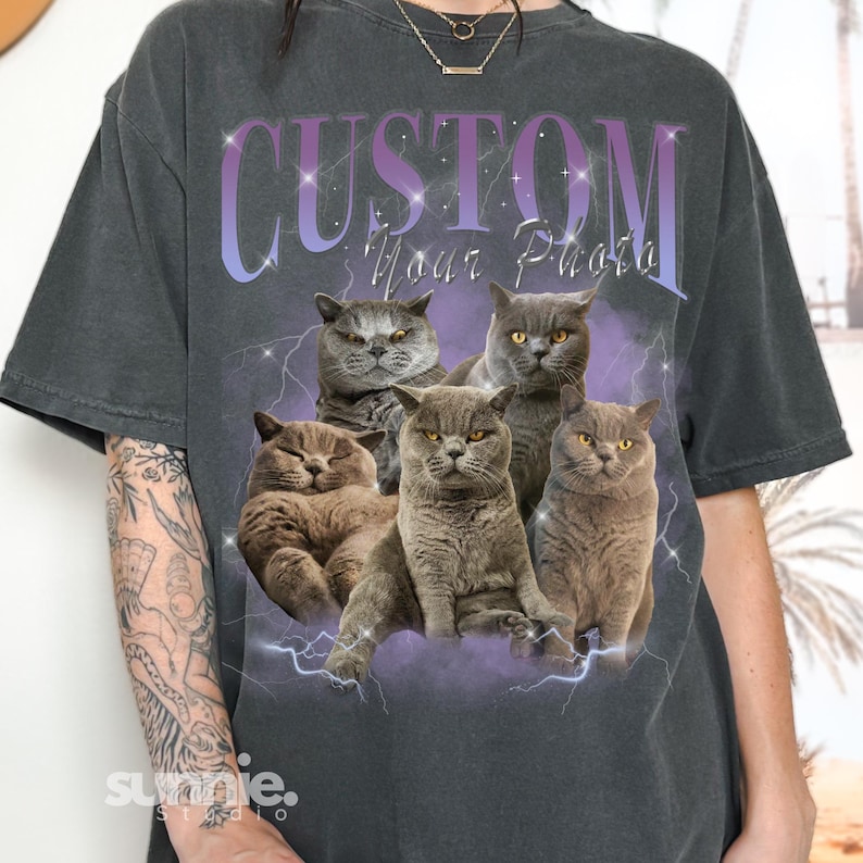 May include: A dark gray t-shirt with a graphic of five gray cats and the text "CUSTOM Your Photo" in purple and white. The graphic is surrounded by white lightning bolts.