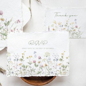 May include: Three white cards with a watercolor floral design and green text. The top card says "Thank you". The middle card says "RSVP" and "Kindly reply by the first of December". The bottom card has a floral design.