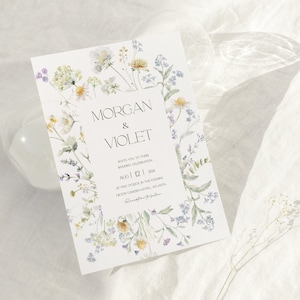 May include: A wedding invitation with a floral design featuring watercolor illustrations of purple, yellow, and green flowers. The text on the invitation reads "Morgan & Violet" and includes the date "Aug 12, 2024".