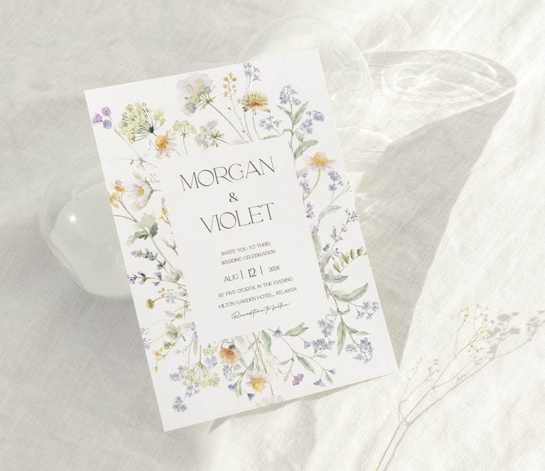 May include: A wedding invitation with a floral design featuring watercolor illustrations of purple, yellow, and green flowers. The text on the invitation reads "Morgan & Violet" and includes the date "Aug 12, 2024".