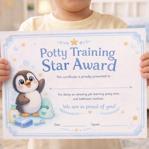 Puede incluir: Un niño sostiene un certificado "Potty Training Star Award" azul claro y blanco. El certificado presenta un pingüino de dibujos animados, burbujas y estrellas. El texto dice "We are so proud of you!"