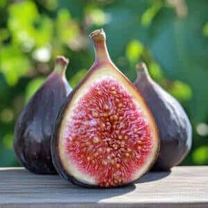 May include: Close-up of three figs, one cut in half to reveal the vibrant red and white interior. The figs have a dark purple exterior and are set against a blurred green background.