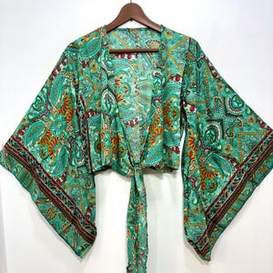 May include: A teal paisley-patterned kimono top with wide, bell sleeves. The lightweight fabric features a repeating design in shades of teal, orange, and burgundy. The top is tied at the waist with a matching fabric tie.