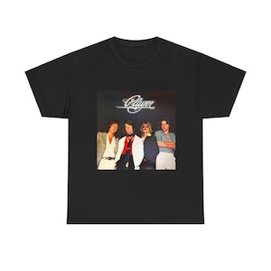 May include: Black t-shirt featuring a vintage image of the band Player. The image shows four men in various outfits, with the band's name in a stylized font above them. A classic music-themed tee.