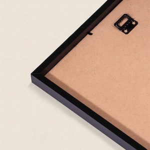 a black frame with a piece of paper inside it, placed on a white surface.