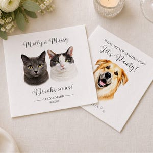 Op de afbeelding: Twee vierkante witte papieren servetten met aangepaste huisdierportretten. E&eacute;n servet toont een grijze kat en een wit-grijze kat met de tekst Molly & Missy, Drinks on us!, Lucy & Mark, 06.07.2026. De andere toont een gouden hond met de tekst What are you waiting for? Let's Pawty!