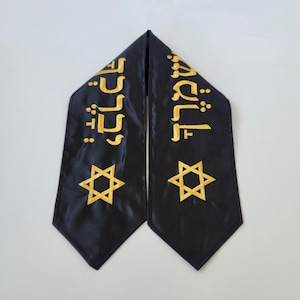 May include: Black satin graduation stole with gold embroidery. The stole features two Star of David symbols and Hebrew text.