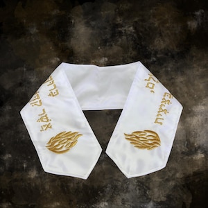May include: White satin stole with gold embroidered Hebrew text and a stylized flame design on each end. The stole is designed to be worn over the shoulders and is likely used for religious or ceremonial purposes.