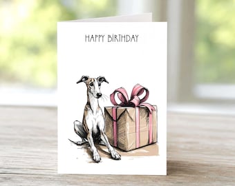 May include: A white greeting card featuring a hand-drawn illustration of a brown and white greyhound sitting next to a tan gift box wrapped with a pink ribbon. The text "HAPPY BIRTHDAY" is printed in black ink at the top of the card.