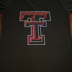 May include: Black t-shirt with a red and black rhinestone Texas Tech University logo.