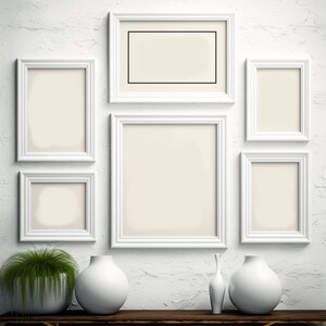 Puede incluir: Una pared blanca con seis marcos de fotos blancos de varios tama&ntilde;os. Los marcos est&aacute;n vac&iacute;os y tienen un paspart&uacute; blanco. Hay tres jarrones de cer&aacute;mica blanca sobre una mesa de madera frente a la pared. Una planta verde est&aacute; en una maceta blanca sobre la mesa.