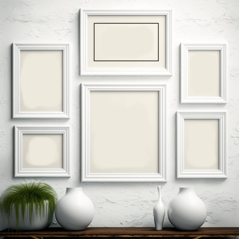 Puede incluir: Una pared blanca con seis marcos de fotos blancos de varios tama&ntilde;os. Los marcos est&aacute;n vac&iacute;os y tienen un paspart&uacute; blanco. Hay tres jarrones de cer&aacute;mica blanca sobre una mesa de madera frente a la pared. Una planta verde est&aacute; en una maceta blanca sobre la mesa.