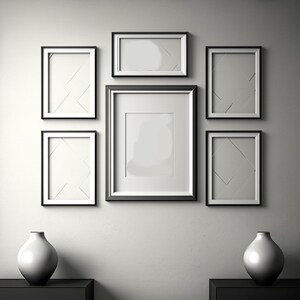 Puede incluir: Una pared blanca con seis marcos de fotos negros de diferentes tama&ntilde;os. Los marcos est&aacute;n dispuestos de forma sim&eacute;trica. Dos jarrones de cer&aacute;mica blanca se encuentran en la parte inferior de la imagen.