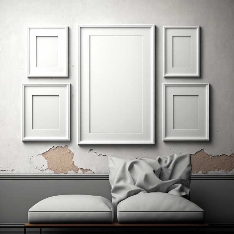 Puede incluir: Cinco marcos de fotos blancos con paspart&uacute; blancos est&aacute;n dispuestos en una pared blanca con textura desgastada. Los marcos est&aacute;n dispuestos en forma rectangular con el marco m&aacute;s grande en el centro. La pared tiene una textura desgastada con algunas &aacute;reas de pintura faltante. Un sof&aacute; blanco con dos cojines est&aacute; en primer plano.