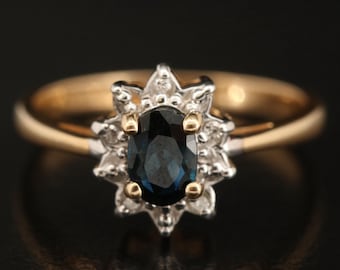 May include: A gold ring with a blue sapphire surrounded by a halo of small diamonds.