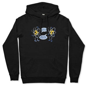 May include: Black hoodie featuring a humorous cartoon of two atoms. One atom says, "Lost an electron?" and the other replies, "Are you positive?" The design includes yellow, blue, and white accents. The hoodie has a front pocket and a hood.