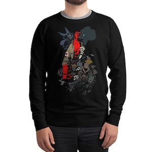 May include: Black sweatshirt featuring a graphic print of a red-skinned character with a crown, surrounded by other characters and skulls.