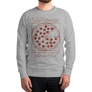 May include: A light gray sweatshirt featuring a pizza design with a Da Vinci-style diagram. The pizza has red pepperoni and is divided into slices. The design includes text in a handwritten font, adding a unique artistic touch.