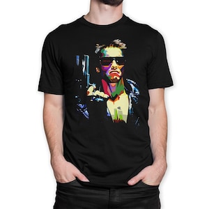 May include: A black t-shirt with a colorful pop art style image of a man wearing sunglasses and holding a gun. The man's face is a mix of red, blue, green, and yellow.