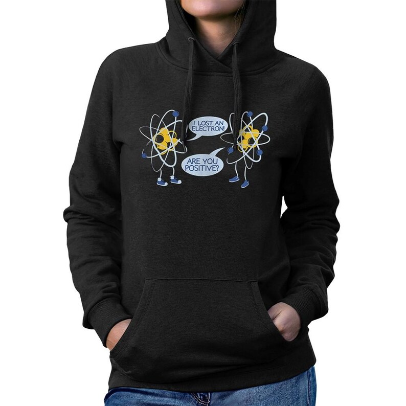 May include: Black hooded sweatshirt with a front pocket. The graphic features two cartoon atoms with speech bubbles that read "I lost an electron" and "Are you positive?"
