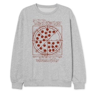 May include: A light gray sweatshirt featuring a pizza design in a red-brown color. The pizza graphic is a circle divided into slices, with text and lines surrounding it. The sweatshirt has a crew neck and long sleeves.