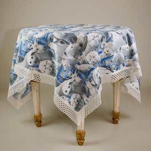 Könnte beinhalten: Ein runder Tischläufer mit einem verspielten Druck von arktischen Tieren in Grau-, Weiß- und Blautönen. Der Tischläufer ist mit einem weißen Spitzenrand versehen und über einem kleinen, antiken Tisch mit verzierten, goldfarbenen Beinen drapiert.