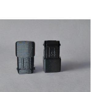 May include: Two black plastic connectors with a textured surface. The connector on the left has a rectangular shape, while the connector on the right has a more complex shape with a raised section.