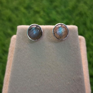 Op de afbeelding: Een paar zilveren oorbel studs met ronde, iriserende labradorite edelstenen.