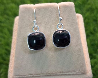 May include: A pair of silver dangle earrings with black square-shaped gemstones.