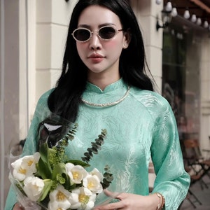 May include: A woman wearing a light green, patterned dress with a white collar and a bouquet of white flowers. She is wearing sunglasses and a necklace. The text "THANKS FOR YOUR FEEDBACK!" is visible in the image.