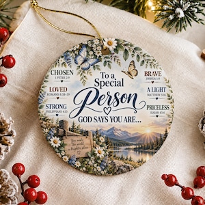 Può includere: Un ornamento rotondo in ceramica raffigurante un paesaggio con montagne, un lago e un'alba. Il testo recita: To a Special Person, GOD SAYS YOU ARE... CHOSEN, LOVED, STRONG, BRAVE, A LIGHT, PRICELESS, e You make the world a brighter place.