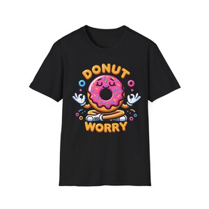 Puede incluir: Camiseta negra con una ilustración de donut meditando con el texto "Donut Worry" en letras amarillas.
