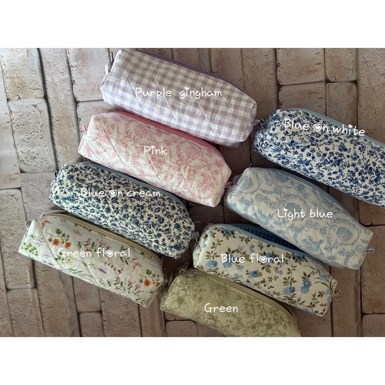 Puede incluir: Ocho estuches rectangulares acolchados con varios patrones que incluyen cuadros vichy morados, toile rosa, floral azul sobre blanco, floral azul sobre crema, toile azul claro, floral verde, floral azul y verde liso con etiquetas.