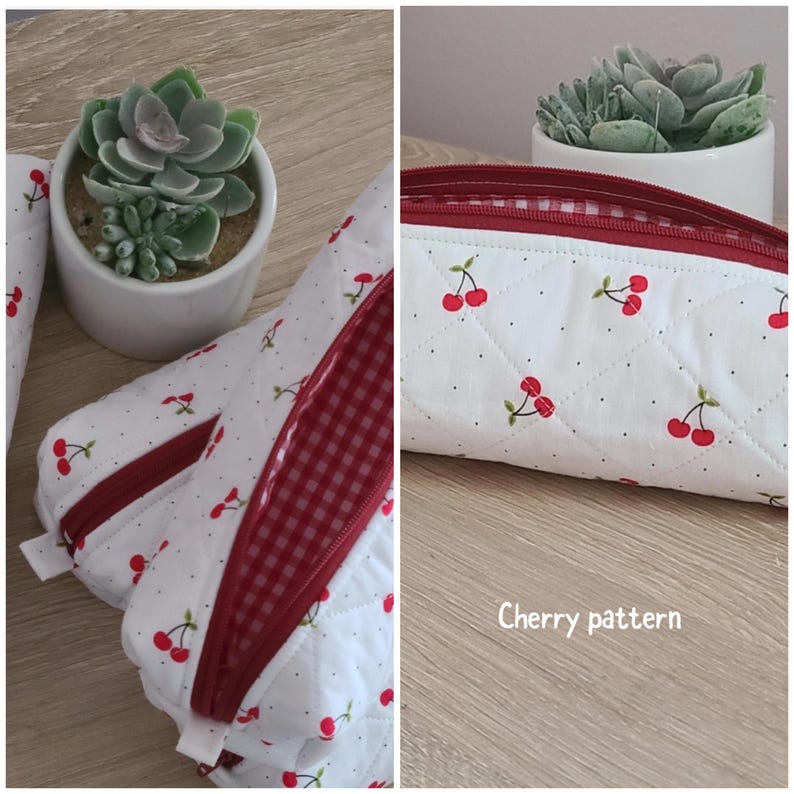 Puede incluir: Un estuche acolchado blanco con un patr&oacute;n de cerezas rojas y peque&ntilde;os puntos negros. El estuche tiene una cremallera roja y un forro interior de cuadros vichy rojos y blancos. El texto Cherry pattern aparece en blanco en la parte inferior.