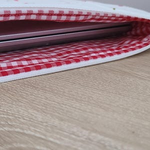 a laptop bag with a red and white checkered pattern, placed on a wooden surface.