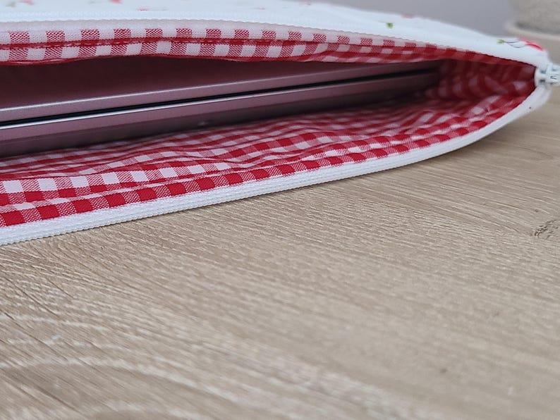 a laptop bag with a red and white checkered pattern, placed on a wooden surface.