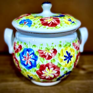Puede incluir: Olla de cerámica blanca con tapa, decorada con diseños florales pintados a mano en tonos de azul, rojo, amarillo y verde.