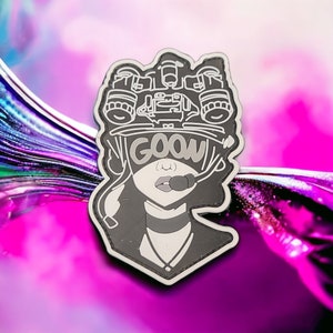 May include: A black and white enamel pin featuring a stylized illustration of a person wearing a helmet with a night vision scope and the word "GOOW" written across the front.