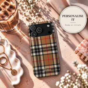 May include: A smartphone case featuring a tan, black, and red plaid pattern with the name Jessica printed in white script near the bottom. The case has a black camera module cutout with three circular lenses and a flash, designed for a mobile device.